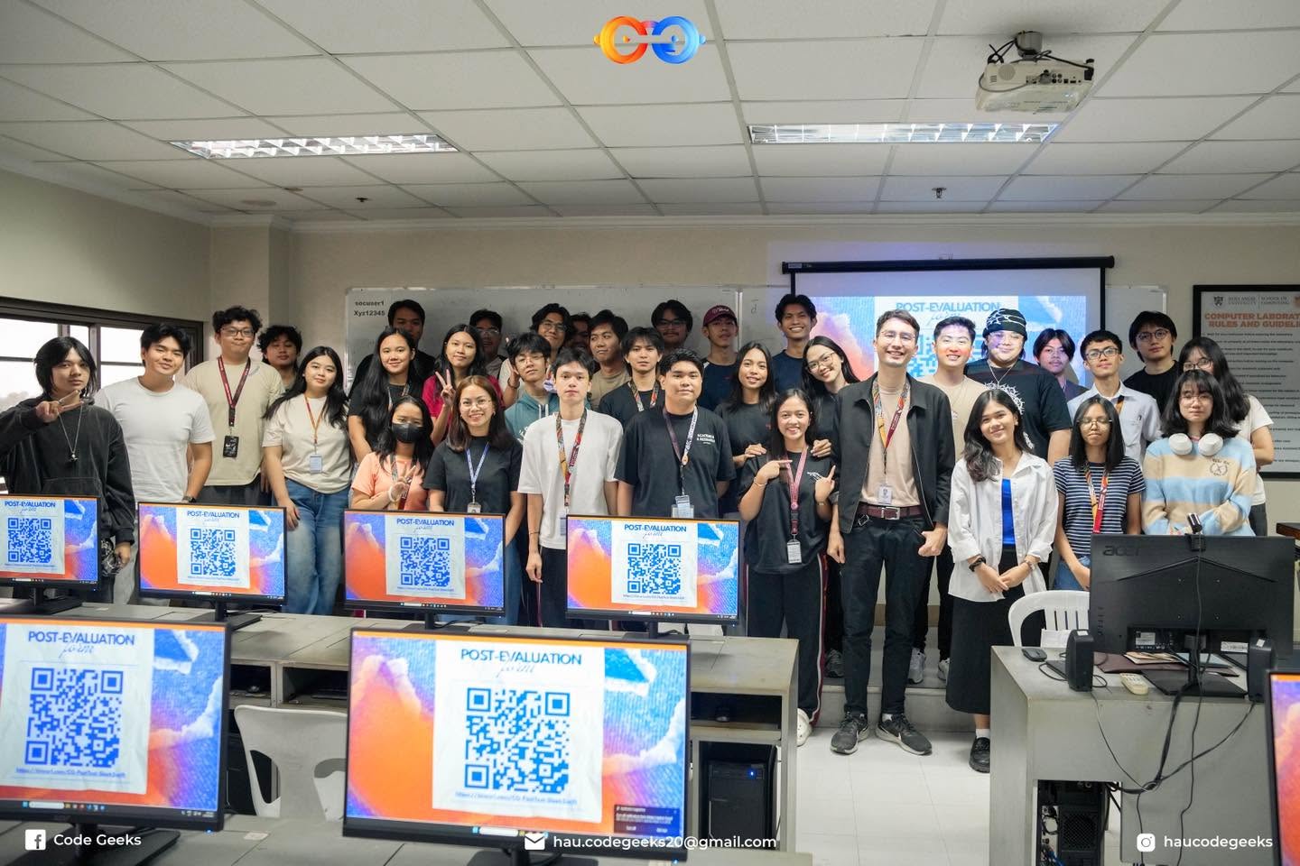 The whole room lined up at the end, every monitor in the foreground showing the post-evaluation form QR code