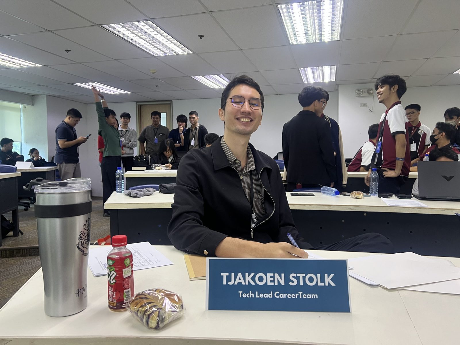 Me at the judging table behind a nameplate reading Tjakoen Stolk, Tech Lead, Career Team, the room still filling up behind me