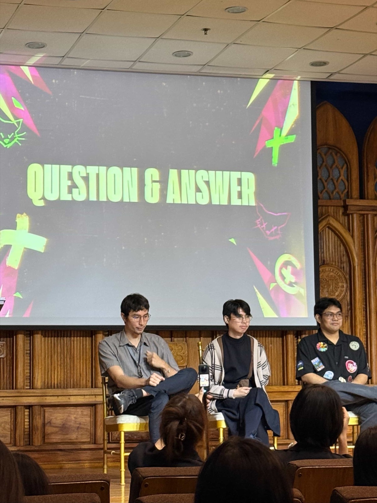 The three speakers seated on stage under a slide reading Question and Answer, taking questions from the floor