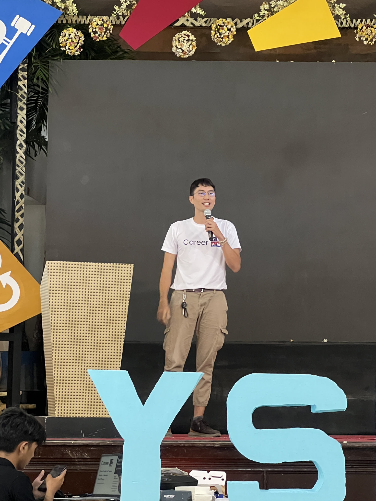 Me mid-sentence with the microphone, the pale blue YSES letters standing along the front of the stage